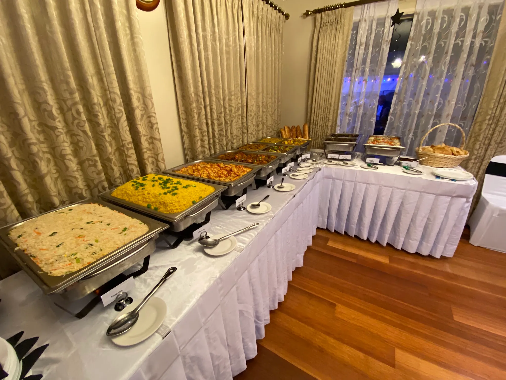 Sri Lankan buffet catering spread with chafing dishes in a warmly lit curtained venue