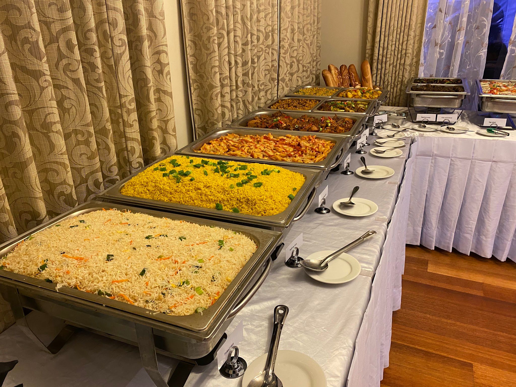 Sri Lankan catering buffet spread with warm lighting, rice and curry dishes in chafing trays